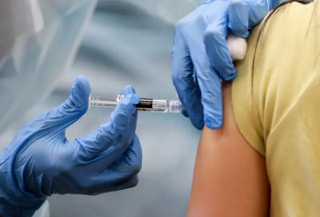 A nurse administers a flu vaccination shot to a woman at a free clinic held at a local library on October 14, 2020 in Lakewood, California