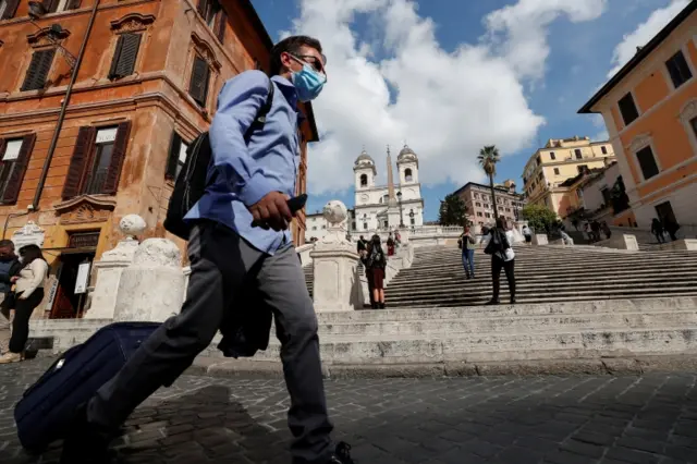 A man wearing a face mask walks past the Spanish Steps in Rome