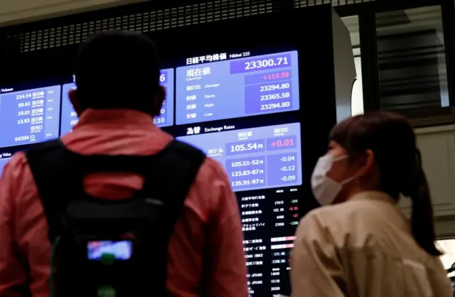 TV crews talk in front of a large screen showing stock prices at the Tokyo Stock Exchange in Tokyo, Japan, 2 October 2020