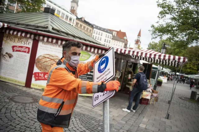 Worker puts up compulsory mask sign in Munich, Bavaria - 24th September