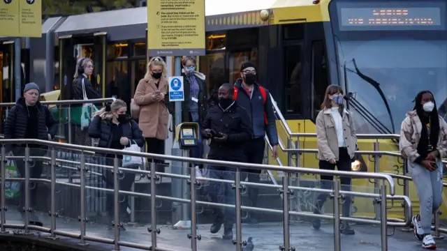 People wearing protective masks get off a tram, amid the outbreak of the coronavirus disease (COVID-19), in Manchester, Britain