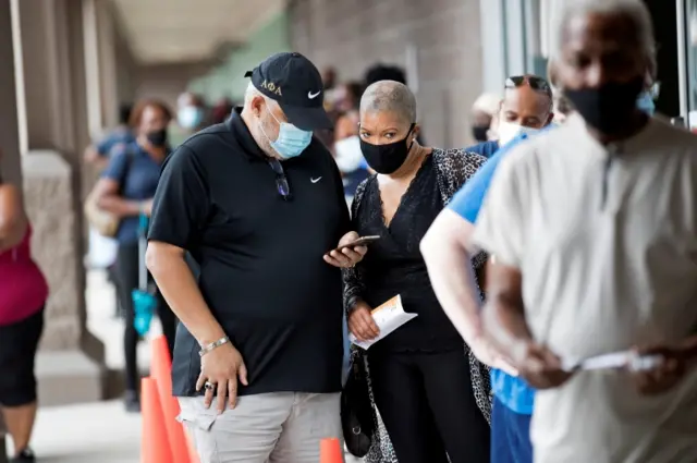 A couple wearing masks wait in line to vote in Orlando, Florida