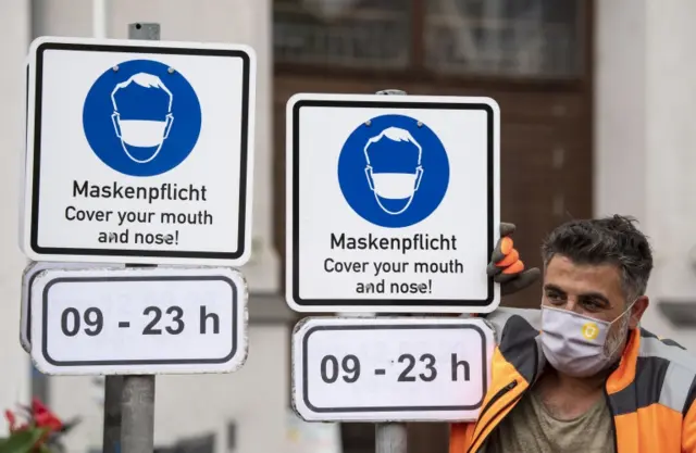 A worker puts up a sign indicating that masks are compulsory in the city center in Munich, Bavaria, Germany, 24 September 2020