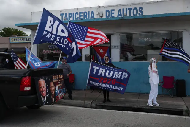 A caravan of supporters for Democratic presidential nominee Joe Biden drive past supporters of President Donald Trump standing on the sidewalk next to the Versailles Restaurant during a Worker Caravan for Biden event on October 18, 2020 in Miami, Florida