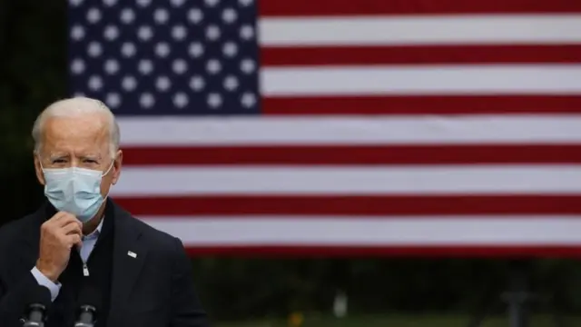 Joe Biden stands at a mic in front of an American flag