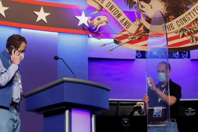 Worker cleans the plexiglass shield between the two candidates in the debate at Belmont University in Nashville, Tennessee, 21 October, 2020