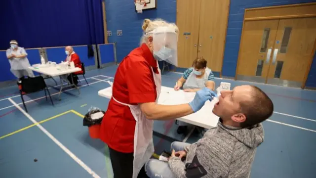 A health worker takes a swab from a man for Covid-19 test at a Stoke-on-Trent City Council facility