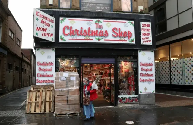 A woman in a face covering walks past a Christmas shop in Sheffield