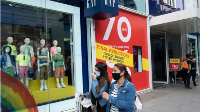 Two women walk past a GAP store