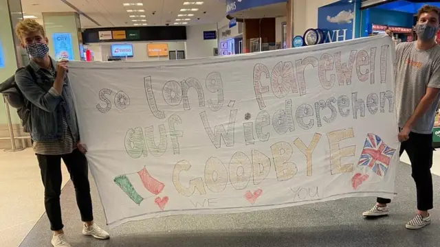 Rhys James (left) and Quinn Paczesny show off a banner at the airport