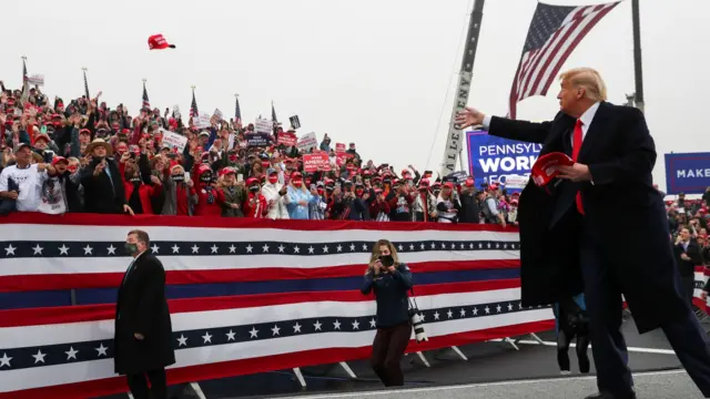 US President Donald Trump throws a "Make America Great Again" cap into the crowd during a campaign event, in Lititz, Pennsylvania