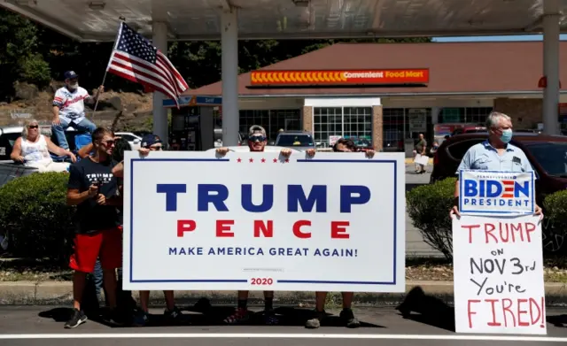 A man with a Biden sign stands next to a group of Trump supporters in Old Forge, Pennsylvania