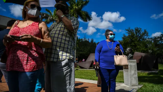 Yrayda Guanipa, 58, (R) stand in line to vote at Westchester Regional Library in Miami, on October 23, 2020.