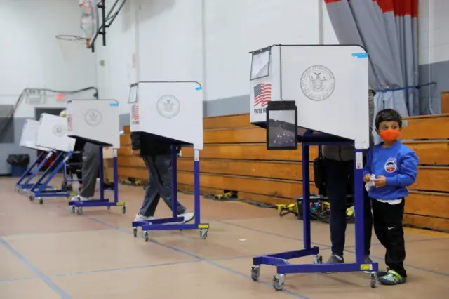 A child waits by a privacy booth as a ballot is filled at a polling station located in the Monsignor John D. Burke Memorial Gym at the Church of the Holy Child in Staten Island, during early voting in New York City, U.S., October 25, 2020.