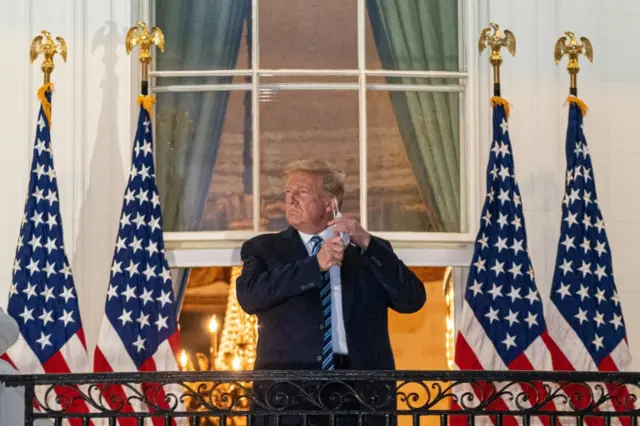 US President Donald Trump takes off his mask after returning to the White House from hospital, 5 October