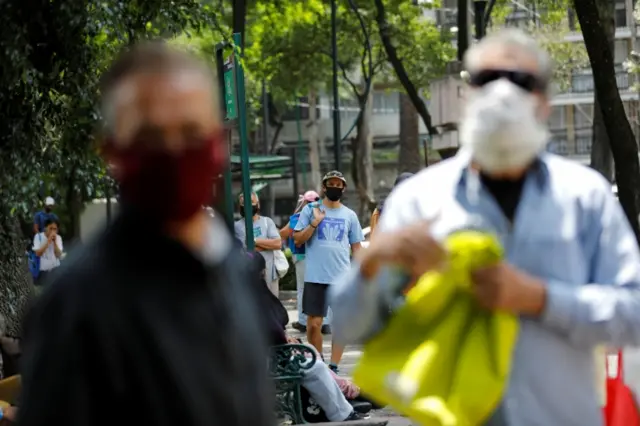 People walk down a street in face masks