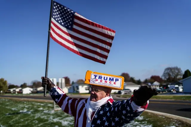 Dave Olson, a supporter of the US president waves a US flag a rally in West Salem, Wisconsin