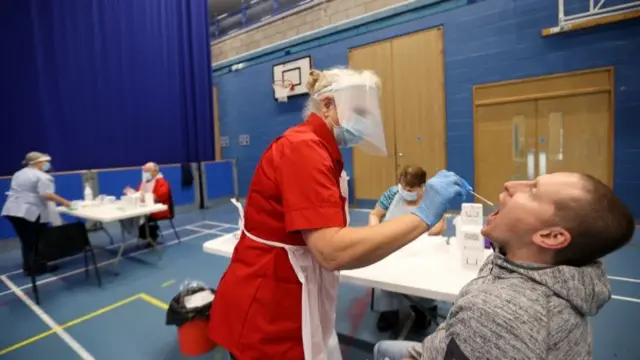 A health worker takes a swab from a man for COVID-19 test