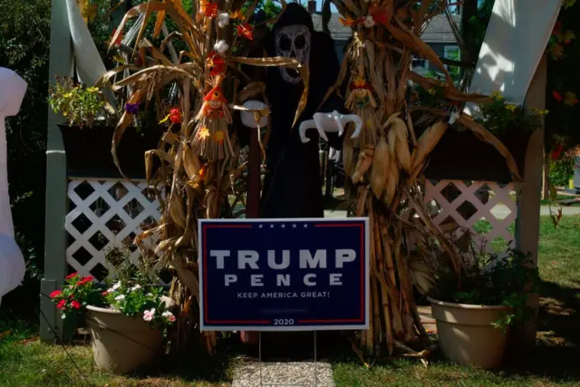 The grim reaper and other Halloween decorations frame a Trump Pence election sign in Michigan