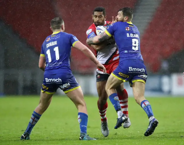 Salford Red Devils' Sebastine Ikahihifo (centre) tackled by Warrington Wolves' Daryl Clark