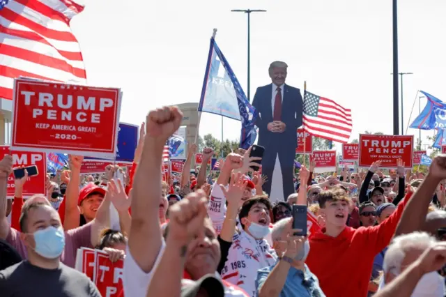 An image of US President Donald Trump is held by supporters at the New York Triumph Rally on Staten Island in New York City on 3 October 2020