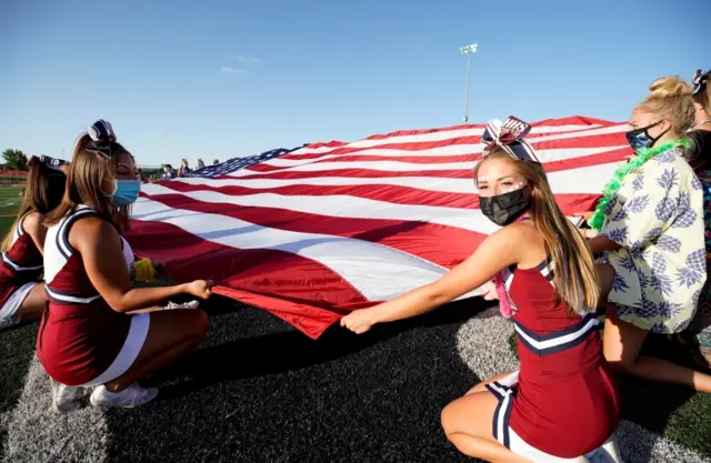 Cheerleaders display the American flag before an American football game in Herriman, Utah. Photo: August 2020