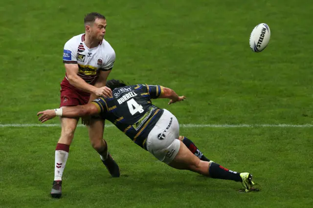 Joe Burgess of Wigan Warriors is tackled by Konrad Hurrell of Leeds