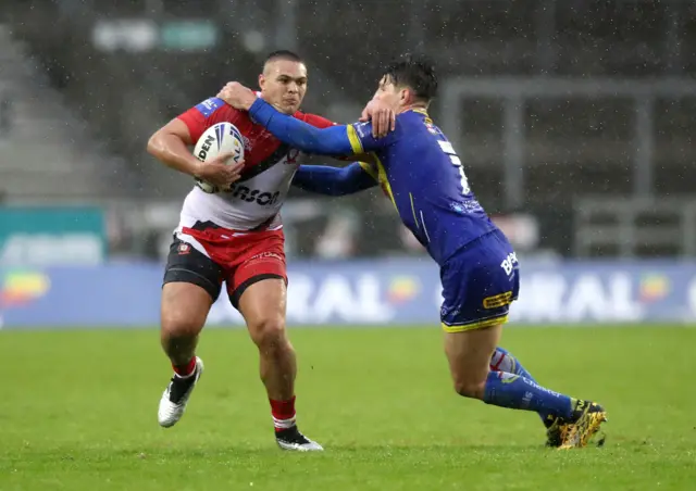 Salford Red Devils' Tui Lolohea (left) tackled by Warrington Wolves' Gareth Widdop