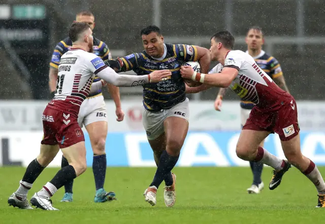 Leeds Rhinos' a Seumanufagai (centre) is tackled by Wigan Warriors' Jackson Hastings