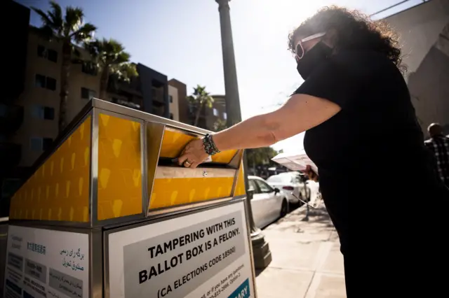 A woman places a ballot in an official mail-in ballot drop box for the US presidential elections in Los Angeles, California, USA, 16 October 2020.