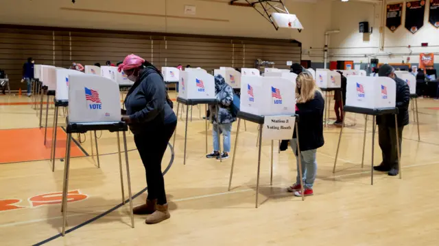 People at voting booths prepare to cast paper ballots at a polling location in Lanham, Maryland, USA, 30 October 2020.