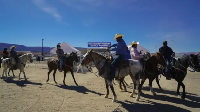 Riders on horseback outside a polling station