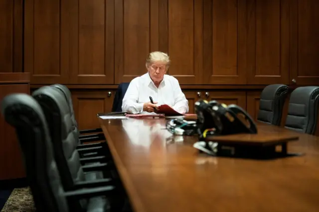 President Donald Trump works in a conference room while receiving treatment in hospital