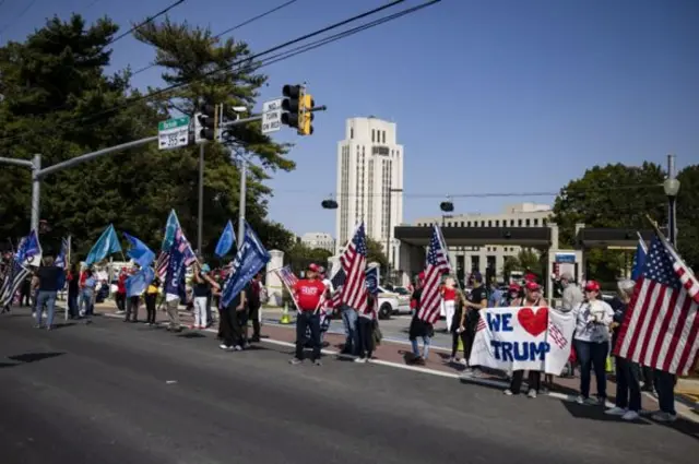 Supporters holding flags wait outside the Walter Reed military hospital