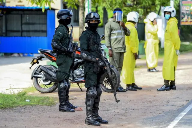 Security personnel stand guard at a checkpoint in Divulapitiya on the outskirts of the Sri Lankan capital of Colombo on October 4, 2020, as police imposed a curfew on the towns of Minuwangoda and Divulapitiya following the discovery of a coronavirus patient, the first case reported from the community after several weeks.