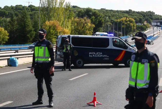 Spanish National Police officers wearing protective masks stand at a traffic checkpoint