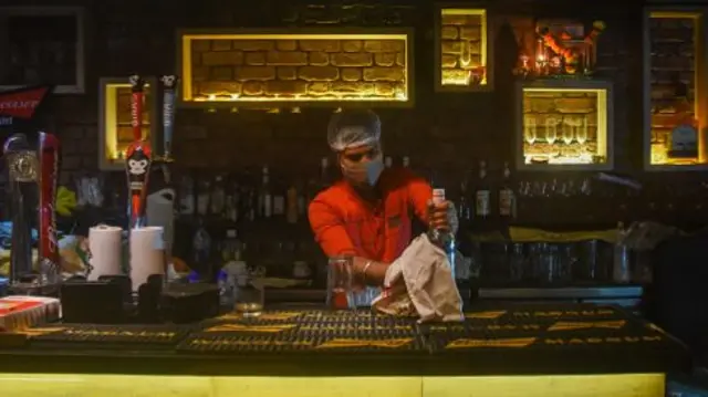 A worker wearing a mask cleans a bar in Mumbai