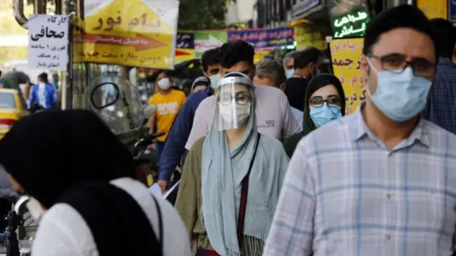 Iranians wearing face masks walk on a street in Tehran, Iran (4 October 2020)