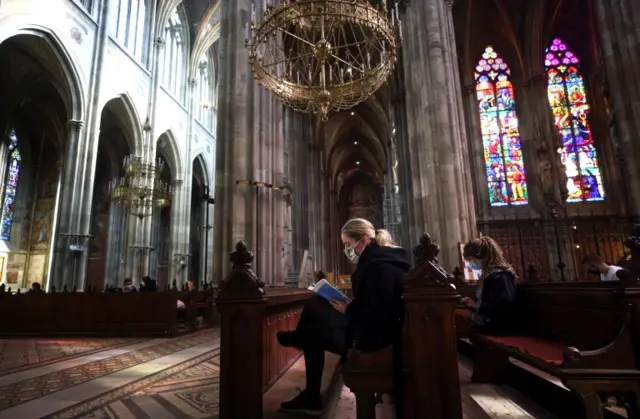 A masked woman reads a book inside Vienna's Votivkirche