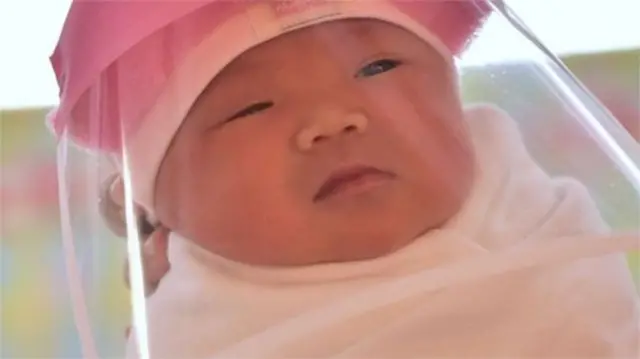 A new-born baby in Singapore wears a face shield