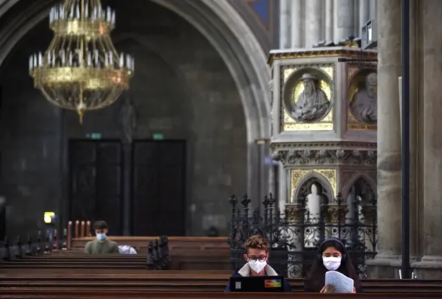 A male and a female student sitting next to each other study in a pew at Vienna's Votivkirche