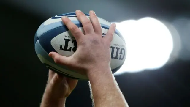 Hands holding rugby ball