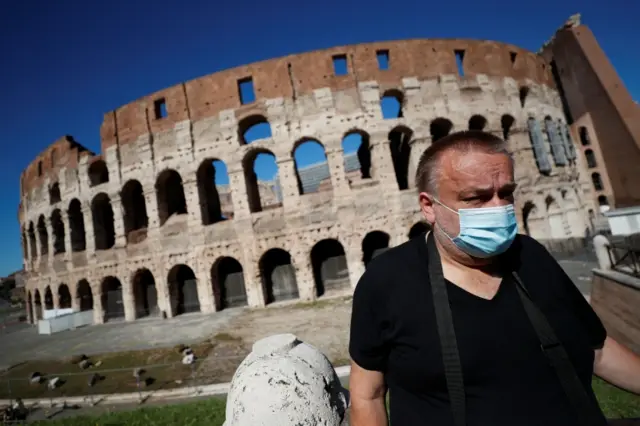 A man wearing a face mask outside the Colosseum in Rome