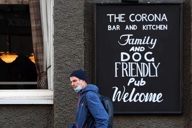 A person with a face covering walks past The Corona pub in Glasgow on Thursday