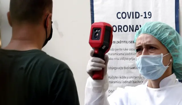 A health worker takes a body temperature of a man at a Covid testing centre in Sarajevo, Bosnia. File photo