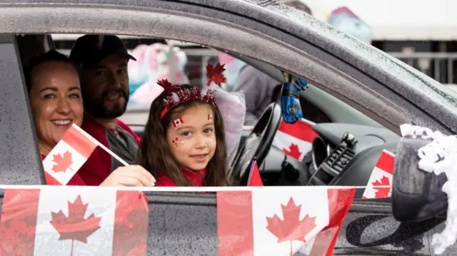 People wave Canadian flags in a car in Vancouver. File photo