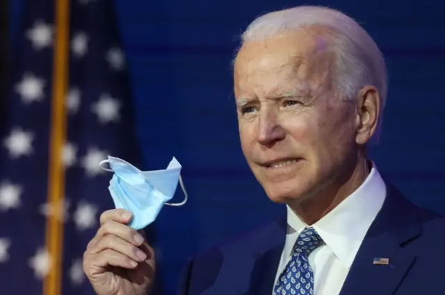 US President-elect Joe Biden holds a face mask as he speaks to reporters about efforts to confront the coronavirus disease