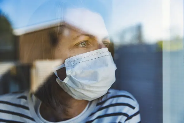 Woman wearing a mask behind a window