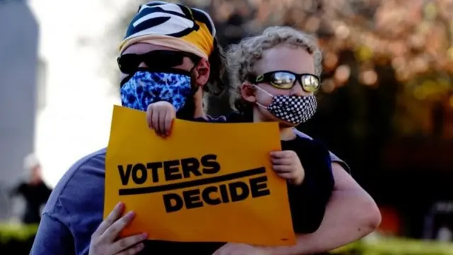 A Biden supporter carries a sign saying "Voters decide"