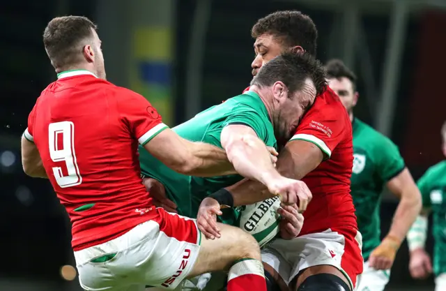 Cian Healy is tackled by Taulupe Faletau and Gareth Davies